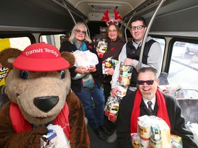 (L-R) Teddy the Transit mascot, Lila Harriman, Dawn Erath, Brian Lorfing, and Calgary Transit Transportation Director Doug Morgan hold just some of the mountains of food donated during the annual Stuff-a-Bus event at the Richmond Rd SW Co-op store in Calgary on  Saturday, November 3, 2018. The annual Stuff-a-Bus food drive for the Food Bank has raised $2 million its 25-year history.  Last yearís event raised more than 51,000 pounds of food and $58,000 in funds. Jim Wells/Postmedia