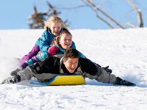 Al Gray with his daughters Jessica,11, and Melissa,5, get some speed tobogganing down St. Andrew's Hill in Calgary on Sunday, Nov. 25, 2018.