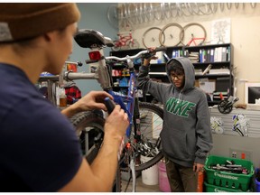 Robyn Cabunoc-Boettcher, bike hub co-ordinator, left helps Om Bhatt, 15, with a bike at Two Wheel View in Calgary, on Dec. 6, 2018. Leah Hennel/Postmedia