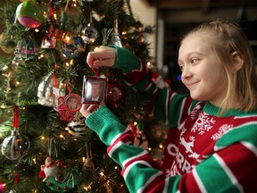 Maisie Endicott, 11,  hangs a photo of her dad, who died in July, on her Christmas tree at her home  in Calgary, on Thursday December 20, 2018. The young girl is hoping she can find the bracelet her dad gave her and had taken in to get sized before he died. Leah Hennel/Postmedia