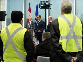 Minister of Natural Resources Amarjeet Sohi is framed by two Yellow Vest protestors as he take part in a press conference to announce $1.6 billion in federal support for Canada's oil and gas sector, in Edmonton Dec. 18, 2018.