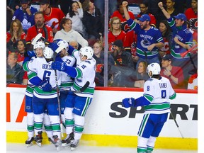 Vancouver Canucks Alex Edler celebrates with teammates after scoring the overtime winner  against the Calgary Flames in NHL hockey at the Scotiabank Saddledome in Calgary on Saturday. Photo by Al Charest/Postmedia.