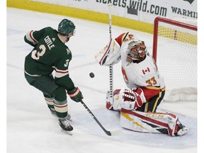 Calgary Flames goaltender David Rittich, of the Czech Republic (33) makes a save as Minnesota Wild center Charlie Coyle (3) skates in during the third period of an NHL hockey game Saturday, Dec. 15, 2018, in St. Paul, Minn. Calgary won 2-1.