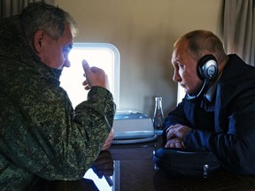 In this file photo taken on Thursday, Sept. 13, 2018, Russian President Vladimir Putin, right, listens to Russian Defence Minister Sergei Shoigu on a board of military helicopter during their flight to attend a military exercises on training ground "Telemba", about 80 kilometres north of the city of Chita during the military exercises Vostok 2018 in Eastern Siberia, Russia.