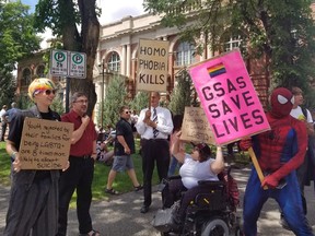 People hold signs outside of a courthouse in Medicine Hat, Alta. on Wednesday, June 20, 2018. A big crowd showed up this morning for the first court challenge to an Alberta law barring schools from telling parents if their children join a gay-straight alliance. A Court of Queen's Bench justice in Medicine Hat is hearing an application from faith-based schools and parents to halt the legislation until there's a ruling on its constitutionality.