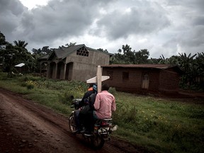 Three Congolese ride a motorbike and carry a cross for a grave along the road linking Mangina to Beni on Aug. 23, 2018 in Mangina, in the North Kivu province. About 300 people have died in the latest outbreak of Ebola in the Democratic Republic of Congo (DRC).