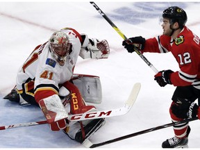 Calgary Flames goalie Mike Smith, left, blocks a shot by Chicago Blackhawks left wing Alex DeBrincat during the third period of an NHL hockey game Sunday, Dec. 2, 2018, in Chicago. The Flames won 3-2.