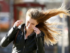 Samantha Walker does her best to battle the haevy winds in downtown Calgary on Tuesday October 17, 2017. Darren Makowichuk/Postmedia