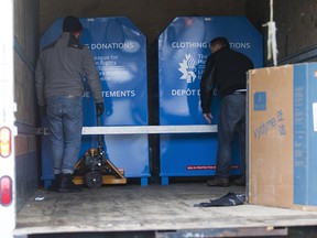 Workmen haul away clothing collection bins after a 35-year-old  Toronto woman died  near Dovercourt and Bloor Street West in Toronto on January 8, 2019.