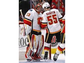 CHICAGO, ILLINOIS - JANUARY 07: David Rittich #33 of the Calgary Flames is congratulated by Noah Hanifin #55 after a win over the Chicago Blackhawks at the United Center on January 07, 2019 in Chicago, Illinois. The Flames defeated the Blackhawks 4-3.