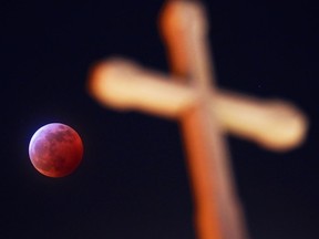 The super blood wolf moon lunar eclipse rises behind a cross on the Ukranian Catholic Church in Renfrew in Calgary on Sunday January 20, 2019.  Gavin Young/Postmedia