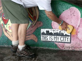 A volunteer cleans a mural made by street artist Ryan Delve among others in Calgary.