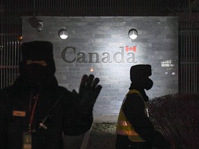 A guard tries to block photos being taken outside the Canadian embassy in Beijing on Jan. 14, 2019.