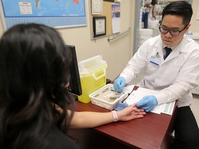 Aaron Lo, pharmacy manager at London Drugs in Calgary, demonstrates a hepatitis C screening test on employee Linh Cosgrove on Tuesday, Jan. 29, 2019.