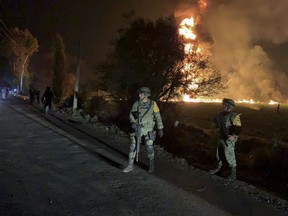 In this image provided by the Secretary of National Defense, soldiers guard in the area near an oil pipeline explosion in Tlahuelilpan, Hidalgo state, Mexico, Friday, Jan. 18, 2019. A huge fire exploded at a pipeline leaking fuel in central Mexico on Friday, killing at least 21 people and badly burning 71 others as locals were collecting the spilling gasoline in buckets and garbage cans, officials said. Officials said the leak was caused by an illegal tap that fuel thieves had drilled into the pipeline in a small town in the state of Hidalgo, about 62 miles (100 kilometers) north of Mexico City. (Secretary of National Defense via AP)