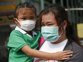 A parent and child wear protective masks for the high levels of air pollution as they leave the school in Bangkok, Thailand, Wednesday, Jan. 30, 2019.