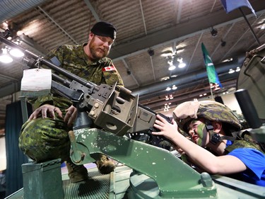 Master Corporal Brandyn Tomayer shows Joshua Keyes some of the equipment at the King's Own Calgary Regiment  booth at the Calgary Boat and Outdoors Show at the BMO Centre on Thursday February 7, 2019. The show continues through the weekend.