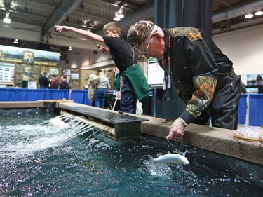 Tom Keoter with the Sarcee Fish and Game Association releases a trout that Matthew Watts has recently caught while he continues to cast at the Calgary Boat and Outdoors Show at the BMO Centre on Thursday February 7, 2019. The show continues through the weekend.