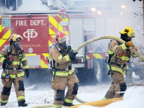 Calgary firefighters move hoses at a large fire which destroyed one home and damaged others in the 300 block of Douglas Glen Close S.E. early Sunday, February 17, 2019.