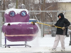 Carl Paswisty cleans up a snow in front of a hippo statue on 17 Ave SE in Calgary Friday, February 15, 2019. Snow is expected this weekend and temperatures look to remain chilly but a possible warm up is in the forecast for early next week. Jim Wells/Postmedia