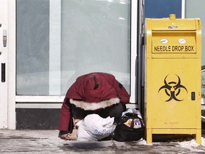 A woman huddles outside of of the Safeworks injection site at the Sheldon Chumir Centre in downtown Calgary Tuesday, February 26, 2019. After a period of time, perhaps 30 min, or more, she was awoken by a friend, had a cigarette, returned to her spot and was then helped inside by Safeworks staff. Jim Wells/Postmedia