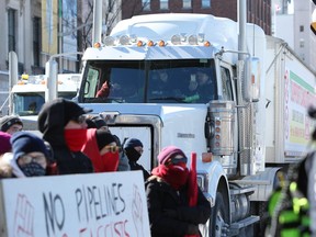 Demonstrators drive a truck past a protest against the United We Roll Convoy For Canada pro-pipeline rally in front of Parliament Hill in Ottawa, Ontario, Canada, on Tuesday, Feb. 19, 2019.
