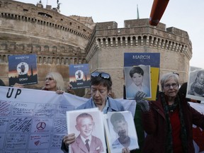 People hold up pictures of what they claim to be victims of priests sexual abuse as they gather during a twilight vigil prayer near Castle Sant' Angelo, in Rome, Thursday, Feb. 21, 2019. Pope Francis opened a landmark sex abuse prevention summit Thursday by warning senior Catholic figures that the faithful are demanding concrete action against predator priests and not just words of condemnation.