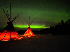 An image of the northern lights set behind two tipis - Yukon northern lights trip