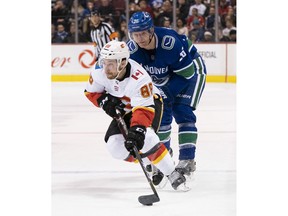 VANCOUVER, BC - FEBRUARY 9: Andrew Mangiapane #88 of the Calgary Flames drives to the net after getting past Antoine Roussel #26 of the Vancouver Canucks in NHL action on February, 9, 2019 at Rogers Arena in Vancouver, British Columbia, Canada.