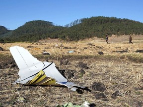 ADDIS ABABA, ETHIOPIA - MARCH 10: A piece of the fuselage of ET Flight 302 can be seen in the foreground as local residents collect debris at the scene where Ethiopian Airlines Flight 302 crashed in a wheat field just outside the town of Bishoftu, 62 kilometers southeast of Addis Ababa on March 10, 2019 in Addis Ababa, Ethiopia. Flight 302 was just 6 minutes into its flight to Nairobi, Kenya, when it crashed killing all 157 passengers and crew on board.