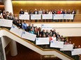 Representatives from 12 charities hold up cheques distributed at the Calgary Herald building from this year's $746,465 raised from the Calgary Herald Christmas Fund on Friday, March 15, 2019.