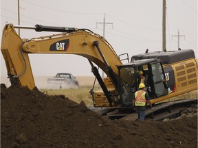 An Enbridge worker digs a ditch under a road to pass Line 3 replacement pipe through just west of Morden, Man.