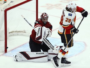The puck hits the post behind Arizona Coyotes goaltender Darcy Kuemper and Calgary Flames Elias Lindholm on Thursday, March 7, 2019, in Glendale, Ariz.