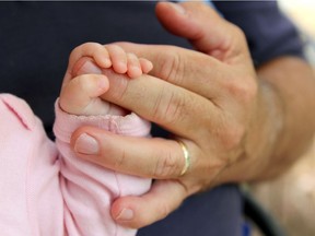 Close up on the Hand of a newborn baby girl holding the finger of her Grandpa lovingly. VIntage style Color. Getty Images/iStockphoto