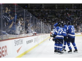 Winnipeg Jets' Mathieu Perreault and his teammates celebrate Perreault's go ahead goal on Calgary Flames goaltender Mike Smith (41) during second period NHL action in Winnipeg on Saturday, March 16, 2019.