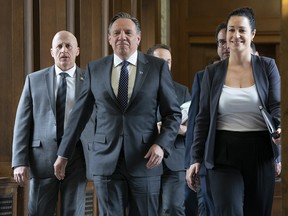 Quebec Premier Francois Legault, centre, walks to question period where his government will table a bill prohibiting public sector employees in positions of authority from wearing religious symbols at work.