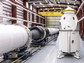 In this Dec. 18, 2018 photo provided by SpaceX, SpaceX's Crew Dragon spacecraft and Falcon 9 rocket are positioned inside the company's hangar at Launch Complex 39A at NASA's Kennedy Space Center in Cape Canaveral, Fla., ahead of the Demo-1 unmanned flight test.