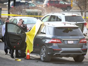 Calgary police inspect a Mercedes SUV at the scene of a double homicide in the northeast this morning.