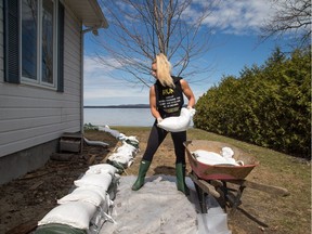 Elisha Wallace lays sandbags alongside her mother's home that looks out over the Ottawa River in the community of Constance Bay, Ont., across from Quebec.