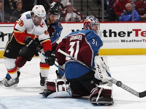 Colorado Avalanche goaltender Philipp Grubauer, front, makes a stick save of a shot as Calgary Flames left wing James Neal, back left, fights for position with Colorado center Tyson Jost during the second period of Game 4 of an NHL hockey playoff series Wednesday, April 17, 2019, in Denver. (AP Photo/David Zalubowski) ORG XMIT: CODZ126