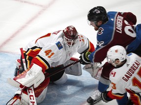 Calgary Flames goaltender Mike Smith, left, stops a shot by Colorado Avalanche left wing Gabriel Landeskog, back right, who drives by Calgary left wing Johnny Gaudreau during the first period of Game 4 of an NHL hockey playoff series Wednesday, April 17, 2019, in Denver. (AP Photo/David Zalubowski) ORG XMIT: CODZ122