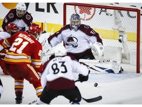 Colorado Avalanche goalie Philipp Grubauer, right, looks on as Calgary Flames' Garnet Hathaway goes for the puck during second period NHL playoff action in Calgary, Thursday, April 11, 2019.THE CANADIAN PRESS/Jeff McIntosh ORG XMIT: JMC127