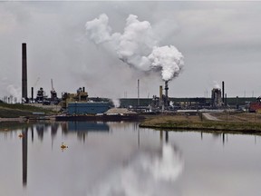 The Syncrude oilsands extraction facility is reflected in a tailings pond near the city of Fort McMurray, Alberta on Sunday June 1, 2014.