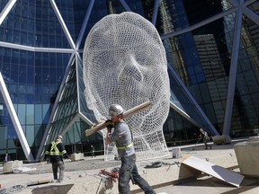 Workers from Armour Equipment clean up their scaffolding after the Wonderland sculpture at The Bow was covered up and repainted in Calgary on Thursday, April 4, 2019. Darren Makowichuk/Postmedia