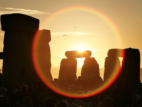 WILTSHIRE, UNITED KINGDOM - JUNE 21:  People watch the midsummer sun as it rises over the megalithic monument of Stonehenge on June 21, 2005 on Salisbury Plain, England. Crowds gathered at the ancient stone circle to celebrate the Summer Solstice; the longest day of the year in the Northern Hemisphere.