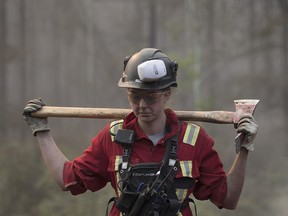 A firefighter works to control a wildfire near the town of High Level on May 24, 2019. Two massive fires have consumed more than 275,000 hectares of forest, as of May 31.