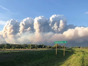 Smoke from wildfires rises into the sky near Paddle Prairie, south of High Level on Friday, May 31, 2019, in this photo provided by Pudgin Wanuch. Wanuch lost his home in the fire.