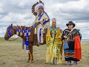 Darren High Eagle, dressed in men's war bonnet, also called buckskin, left, Astokomii Smith, 2019 Calgary Stampede First Nation Princess, and Marilyn Little Chief in a traditional outfit pose for a photo at Blackfoot Crossing Historical Park during the National Indigenous Peoples day celebrations on on Friday, June 21, 2019.