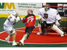 Calgary Roughnecks star Zach Currier, middle, collides with Vancouver Warriors Joel McCready, left, as he tries to score on Warriors goalie Aaron Bold during their game at the Scotiabank Saddledome in Calgary, on Saturday December 15, 2018. Leah Hennel/Postmedia