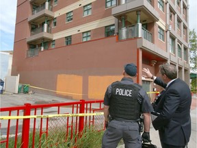 Calgary Police Forensics Unit members and ASIRT Team Commander Gary Creasser investigate outside an apartment building balcony at Riverfront Ave and 1 St SE in downtown Calgary on Wednesday, June 19, 2019. Accordiing to Police, a woman went over a 5th floor balcony railing as police executed a high-risk search warrant. She later died from injuries.